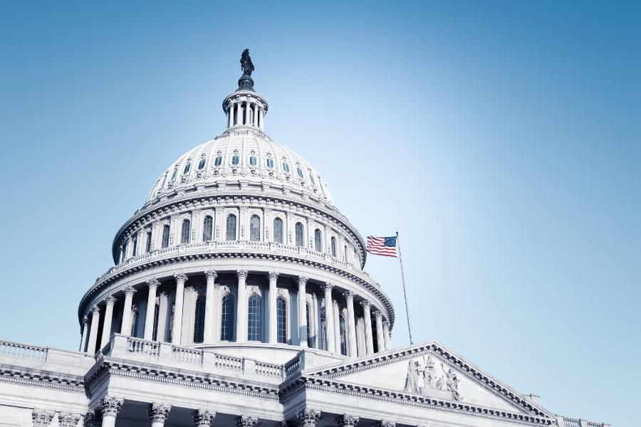 Top of the U.S. Capitol building with the American Flag standing standing on the roof. 